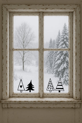 vier schwarze Vinyl-Fensteraufkleber in Tannen-Form auf Scheibe vor winterlicher Landschaft – minimalistische Weihnachtsdeko